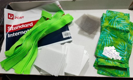 Cut pieces of fabric, plastic for pockets, inner stiffening fabric, and cotton webbing loops