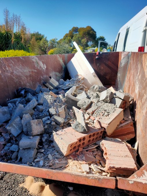 A nearly full skip bin containing all the old tiles, fittings etc. from the en suite bathroom and toilet 